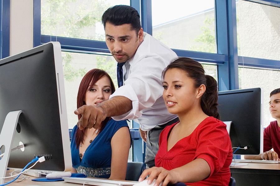 Teacher pointing over student at computer