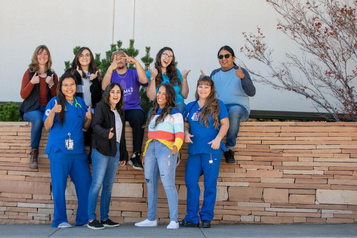 Group of 9 SJC Students sitting on an outside wall.